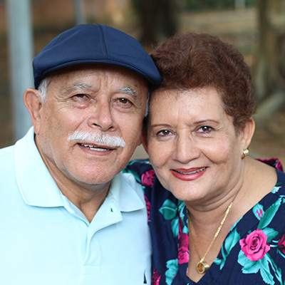 elderly couple, man is wearing a cap and woman is wearing a flowered blouse.